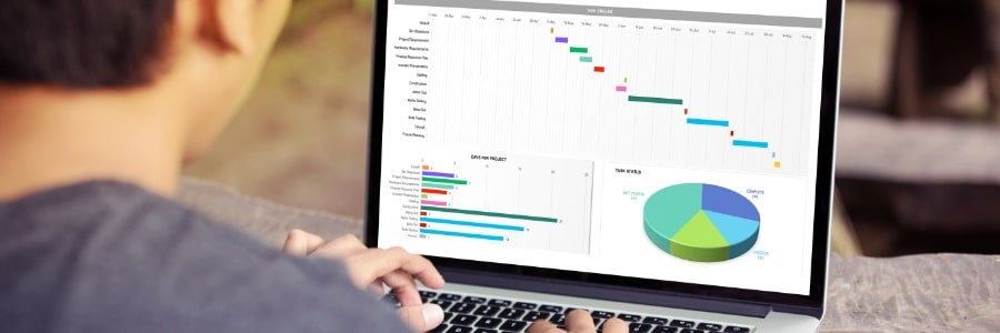 A man is looking at a laptop screen which is currently showing data and spreadsheets