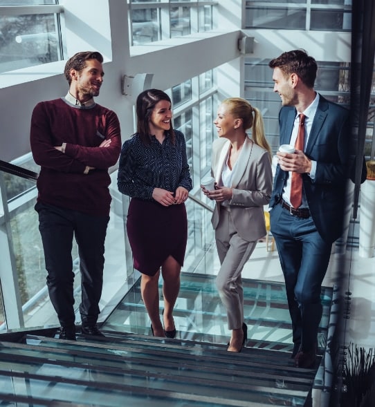 A group of business people walking up a set of glass stairs and talking each other